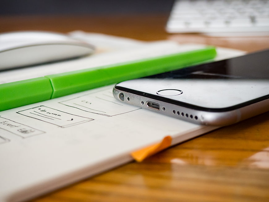 Smartphone and Sketchbook on Wooden Desk