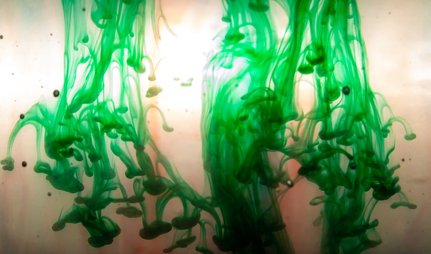 Abstract green ink swirling in water with light background