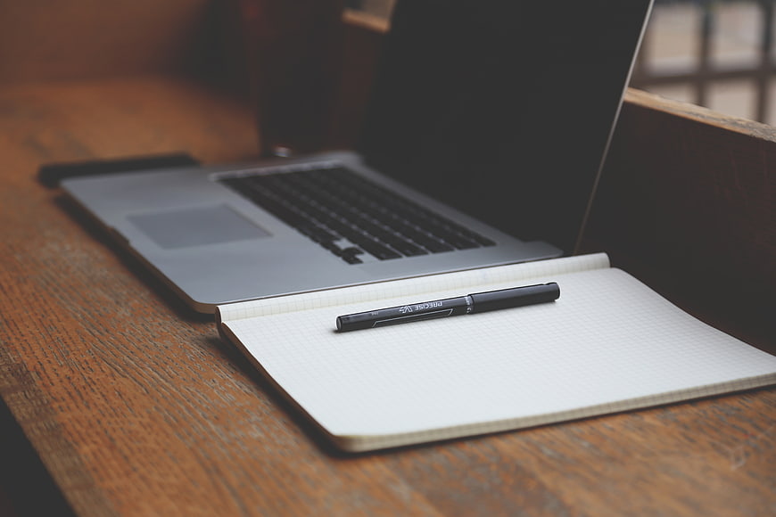 Laptop and notebook on wooden desk workspace
