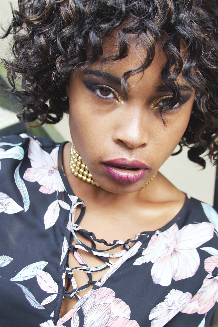 Portrait of stylish woman with curly hair and gold makeup