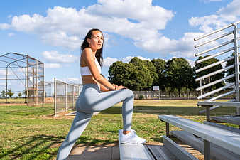 Woman stretching leg on outdoor stadium bleachers