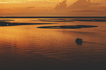 Boat sailing on river at golden sunset