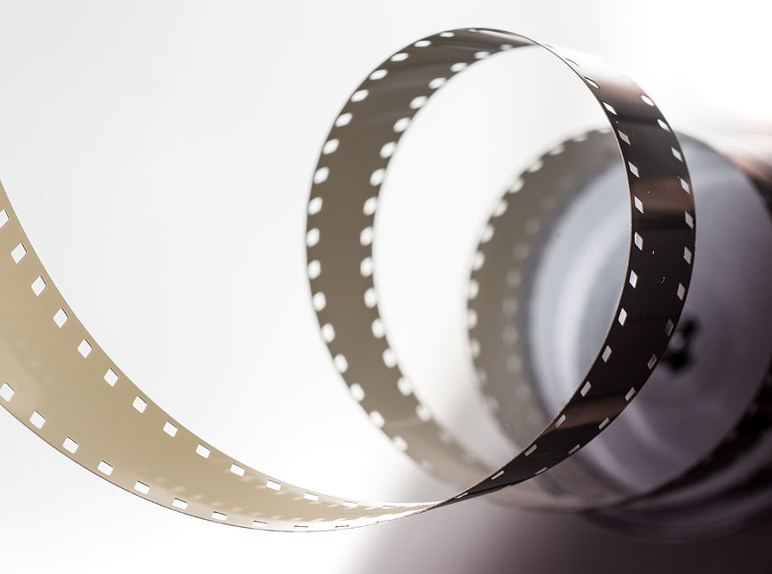 Vintage 8mm film strip unspooling from reel on white background