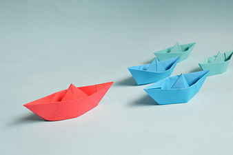 Red Origami Boat Leading Blue Paper Ships on Blue Background