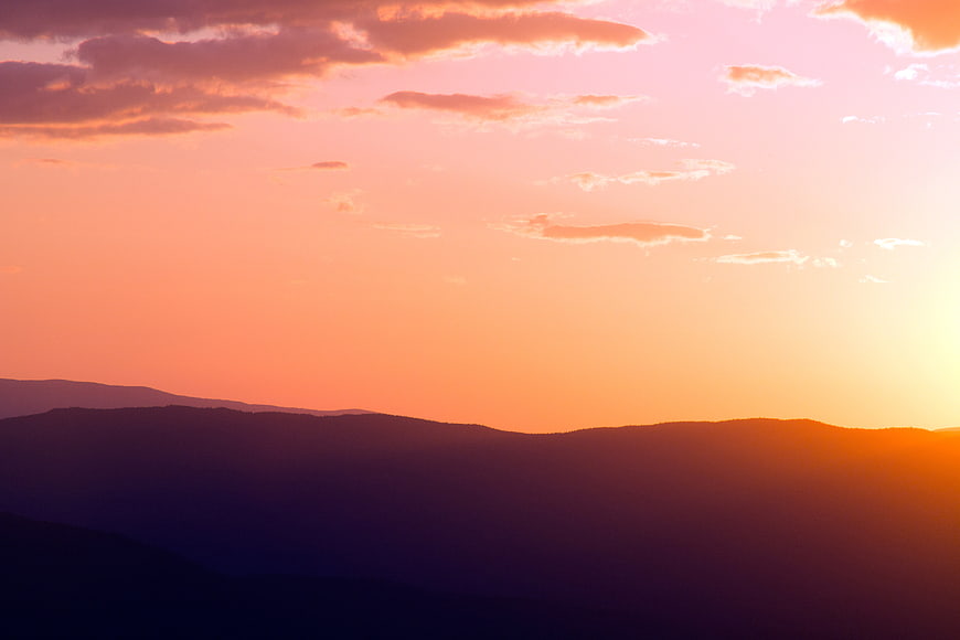 Vibrant Pink and Orange Sunset Over Mountain Silhouettes