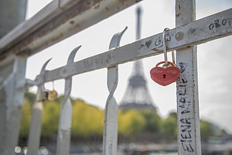 Red heart padlock on Paris bridge railing with Eiffel Tower background