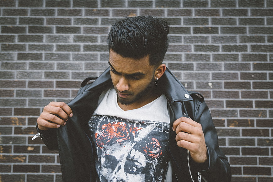 Young man in leather jacket against brick wall