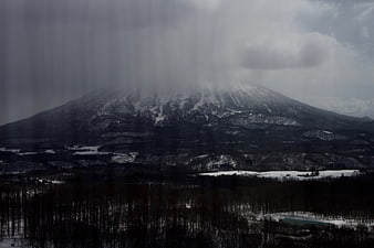Snowy Mountain Landscape with Dark Forest and Overcast Sky