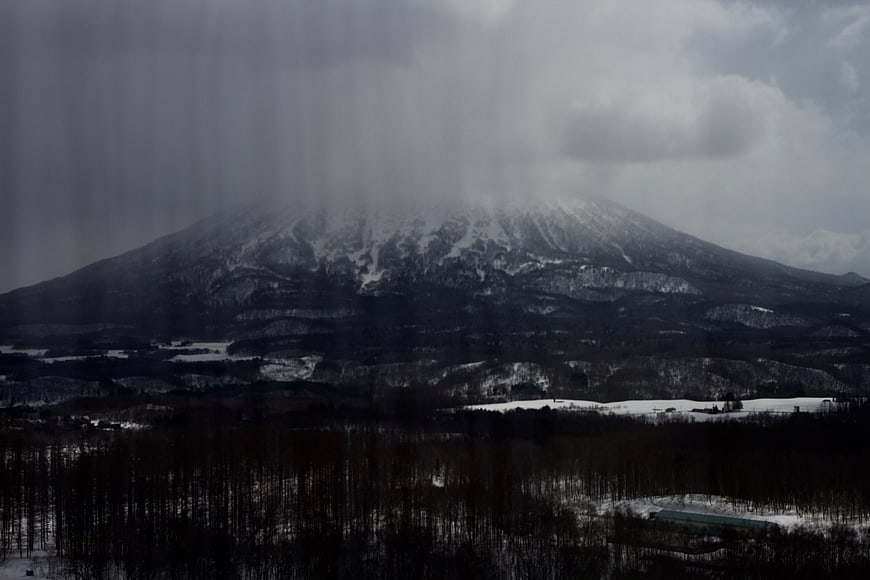 Snowy Mountain Landscape with Dark Forest and Overcast Sky