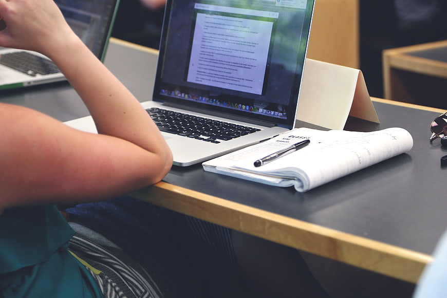 Student studying with laptop and notebook at desk