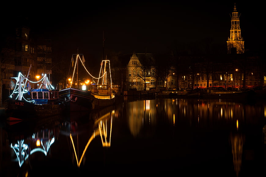 Night view of Groningen canal with illuminated boats and reflections