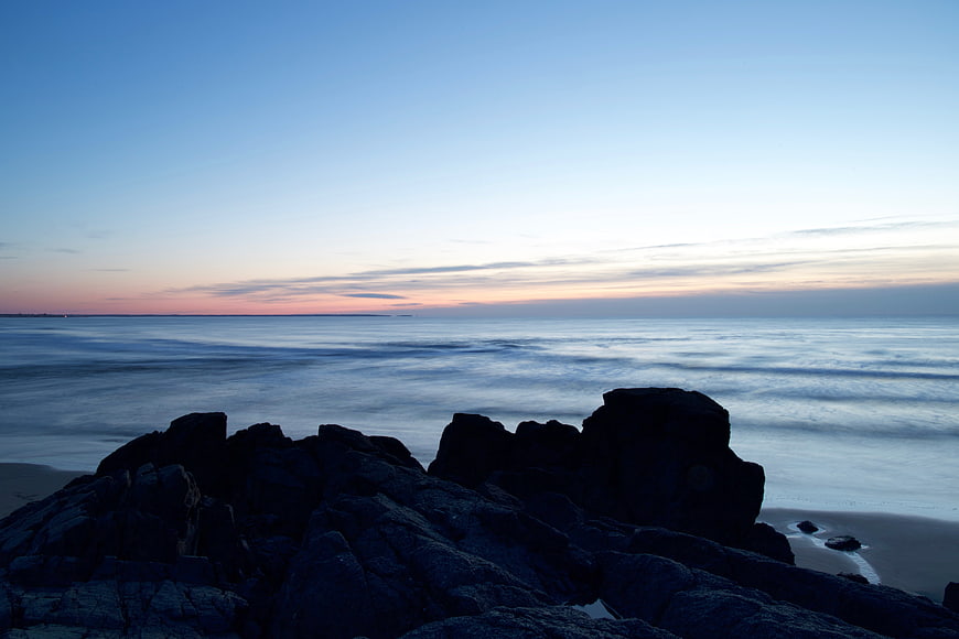 Serene Long Exposure Ocean Sunset with Silhouetted Rocks
