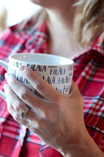 Woman holding festive coffee mug in red plaid shirt