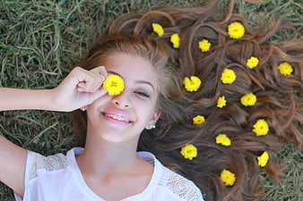 Happy Girl Lying on Grass with Yellow Flowers in Hair