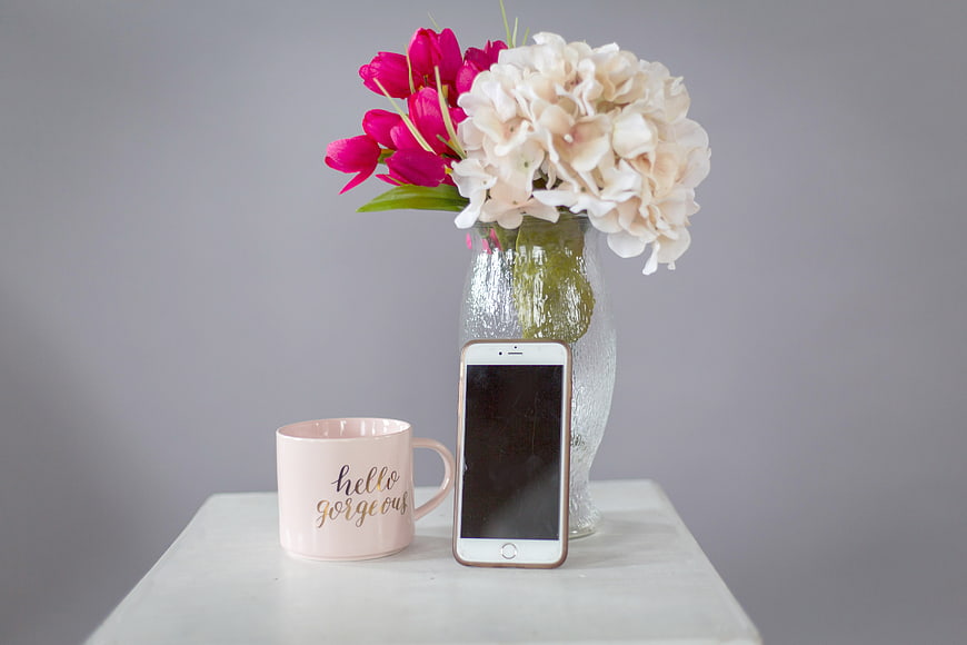 Pink Mug, Smartphone, and Flowers on White Table