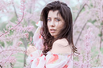 Woman in floral dress amidst pink spring blossoms