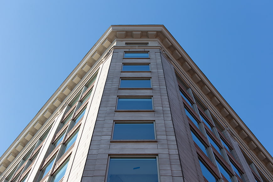 Low angle view of modern office building facade against blue sky