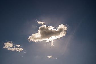Sun rays shining through a single cloud in blue sky