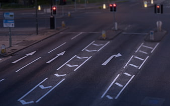 Empty urban road intersection with white directional arrows and traffic lights