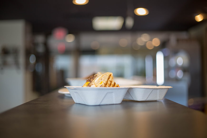 Takeout food in white container on counter with bokeh background