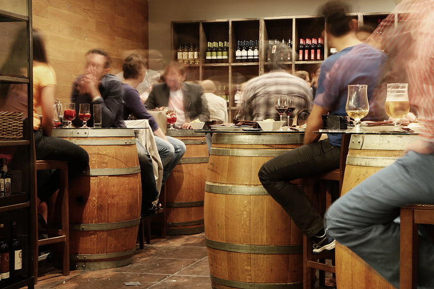 Busy Wine Bar with Wooden Barrel Tables and Patrons
