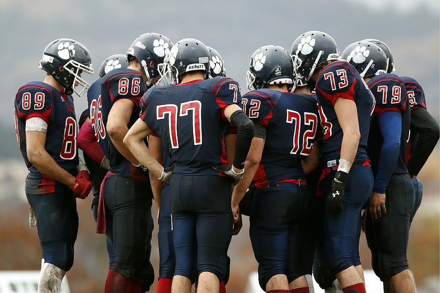 American Football Team Huddle in Navy and Red Uniforms