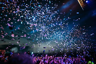 Crowd at concert with falling confetti and stage lights