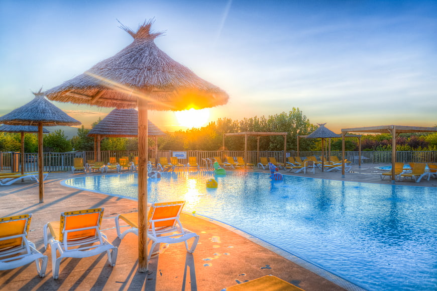 Sunset at Tropical Resort Swimming Pool with Thatched Umbrellas