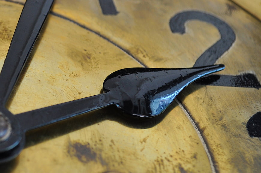 Close-up of vintage clock hands on aged golden face