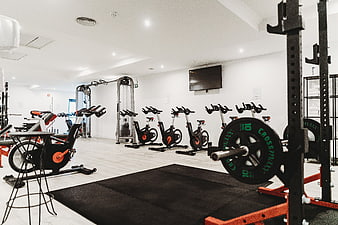 Modern empty gym interior with exercise bikes and weight rack