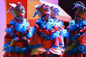 Children in colorful carnival costumes and masks performing on stage