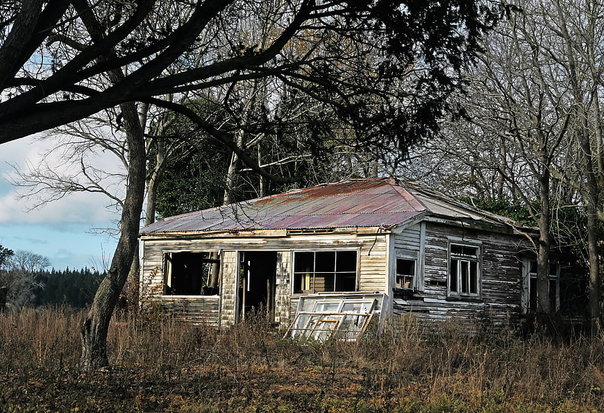 Abandoned Weathered Wooden House in Overgrown Field