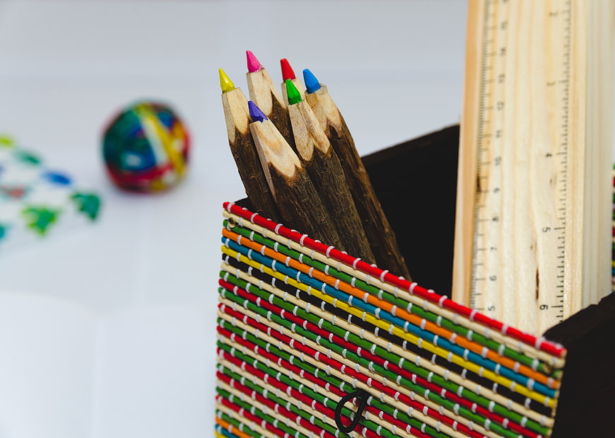 Colorful pencils in woven basket with wooden ruler