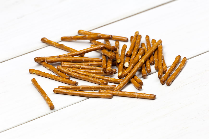 Salted pretzel sticks on white wooden background