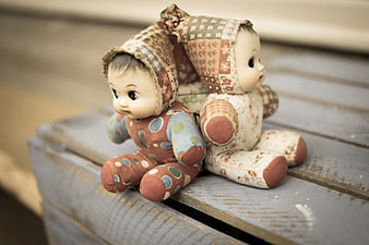 Vintage Rag Dolls Sitting on Weathered Wooden Bench
