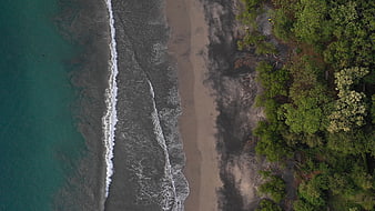 Aerial View of Turquoise Ocean Waves Meeting Sandy Beach and Forest