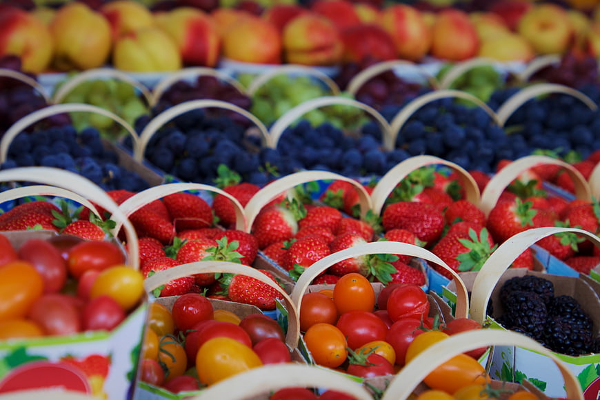 Colorful baskets of fresh berries and tomatoes at a market