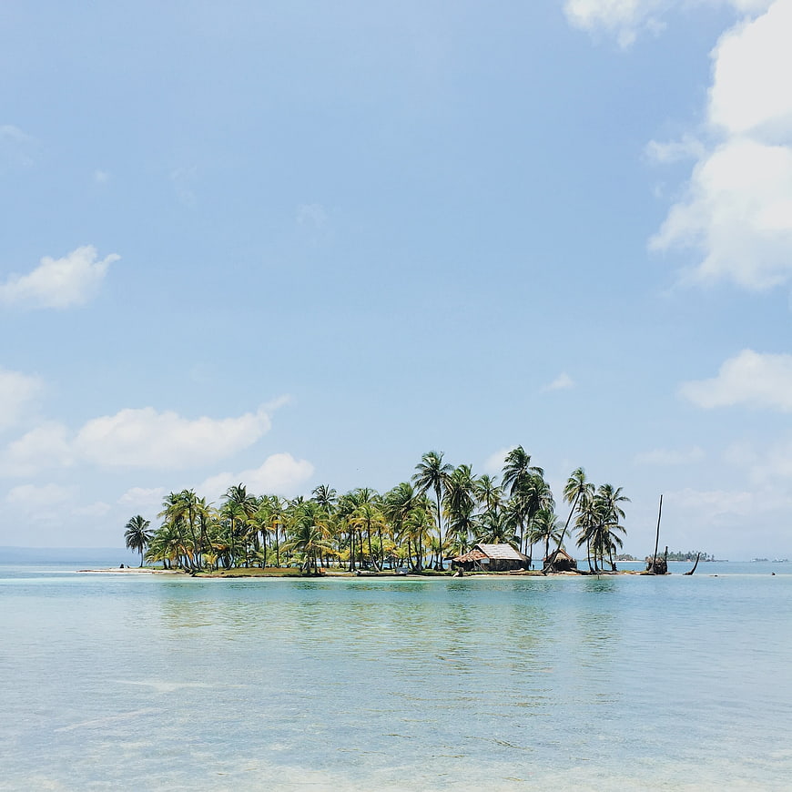 Tropical Island with Palm Trees and Huts in Blue Ocean