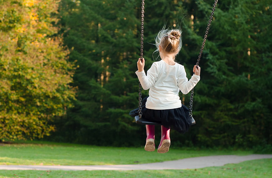 Little Girl on Swing in Park with Autumn Trees