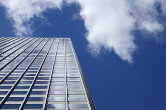 Low angle view of modern glass skyscraper against blue sky