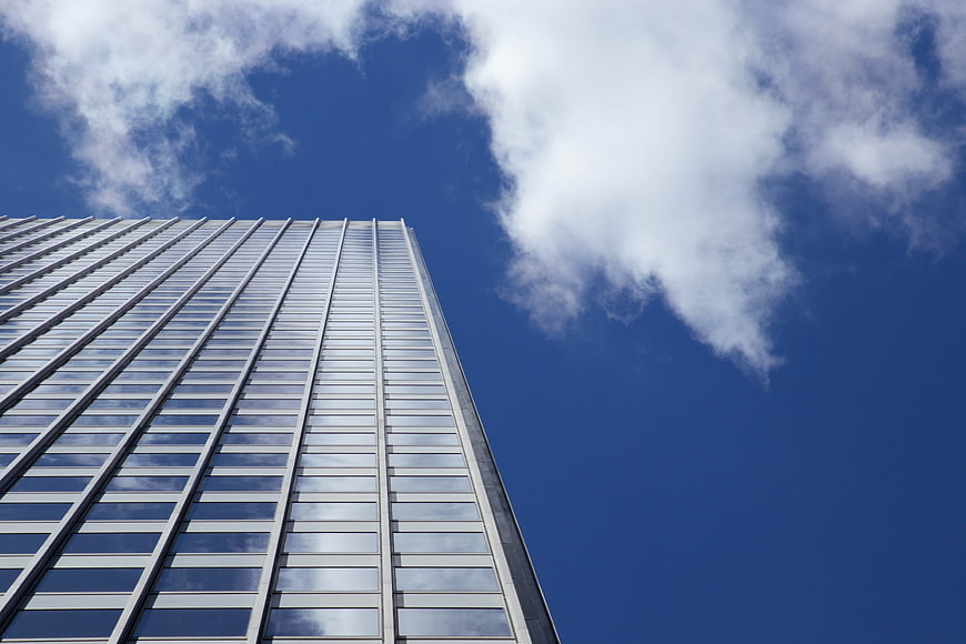 Low angle view of modern glass skyscraper against blue sky