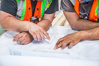 Construction workers reviewing blueprints on site