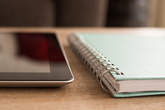 Close-up of tablet and spiral notebook on wooden desk