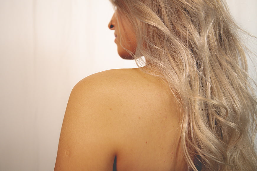 Close-up of blonde woman's shoulder and wavy hair
