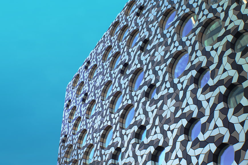 Modern geometric building facade with round windows against blue sky