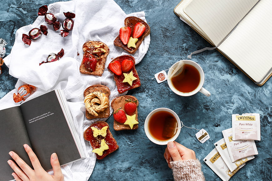 Flat lay of tea, toast, and books on blue background