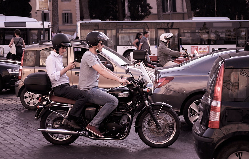 Two men on motorcycle in city traffic