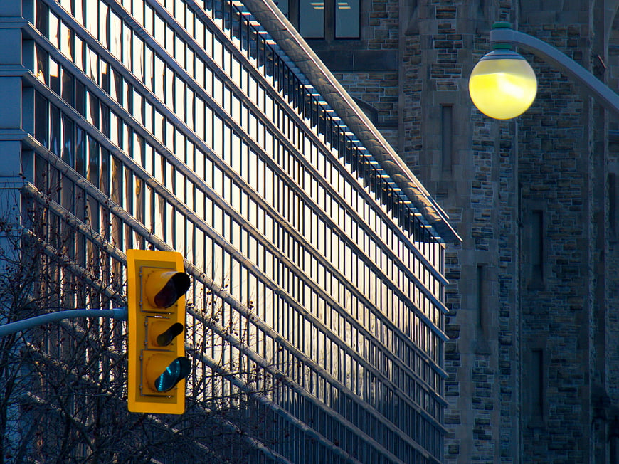Yellow Traffic Light and Street Lamp Against Urban Architecture