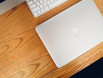 Top View of Closed MacBook and Keyboard on Wooden Desk