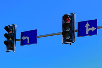 Traffic lights and directional signs against a clear blue sky